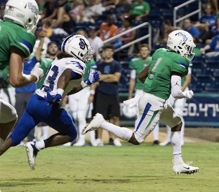 Hiram Velez breaking downfield past a defender in a West Florida uniform.