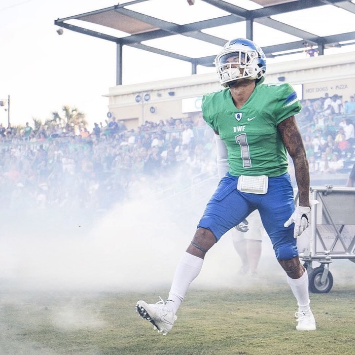 Hiram Velez taking the field through smoke in a West Florida uniform.